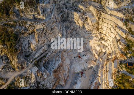 Veduta aerea delle terrazze in marmo scolpito che cadono lungo la montagna, una testimonianza dell'impegno umano contro la grandezza della natura, Carrara, Toscana, Italia. Foto Stock