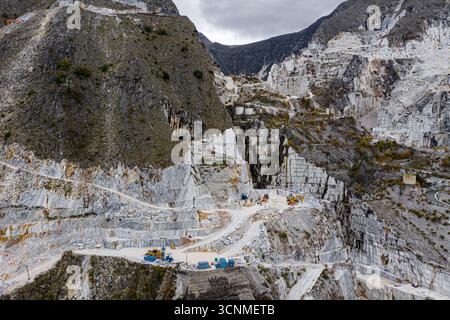 Vista aerea delle terrazze in marmo bianco scuro scolpite sul lato della montagna, rivelando gli intricati strati di pietra, Carrara, Toscana, Italia. Foto Stock