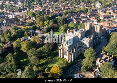 Fotografia aerea della cattedrale di Ripon a Ripon, North Yorkshire, Regno Unito, scattata in un clima limpido di fine estate con cieli azzurri e luce solare calda che mettono in risalto l'impressionante architettura gotica della cattedrale. L'immagine mostra l'elegante fronte occidentale inglese con le sue torri gemelle, intricati lavori in pietra e finestre ad arco, circondati dalle storiche strade della città, dagli edifici vicini, dai tetti e dalle macchie di spazi verdi, tra cui parchi e aree aperte. Questa vista panoramica con drone cattura la posizione centrale della cattedrale nella compatta città medievale, sottolineando il suo ruolo di pietra miliare del patrimonio culturale Foto Stock