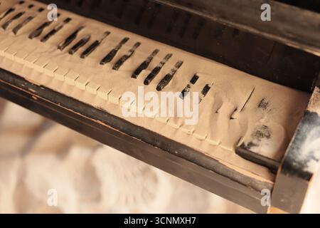 La sabbia copre le chiavi di un vecchio pianoforte in una camera tranquilla Foto Stock