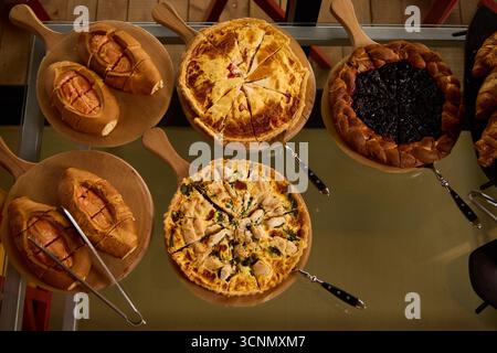 Varietà di piatti al forno esposti su tavole di legno Foto Stock