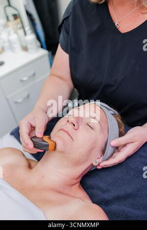 Massaggio linfatico estetista sul viso della donna con spazzola Foto Stock