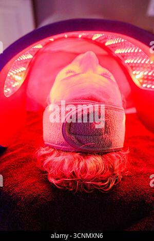Donna sdraiata che riceve una terapia a luce rossa per ringiovanimento della pelle Foto Stock