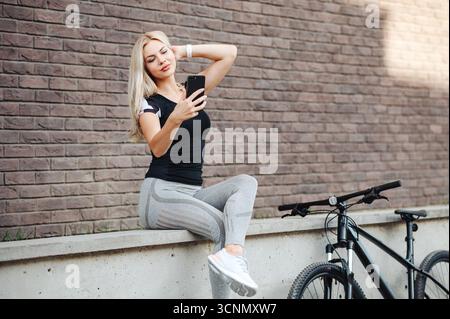 Donna che porta Selfie accanto alla bicicletta Foto Stock