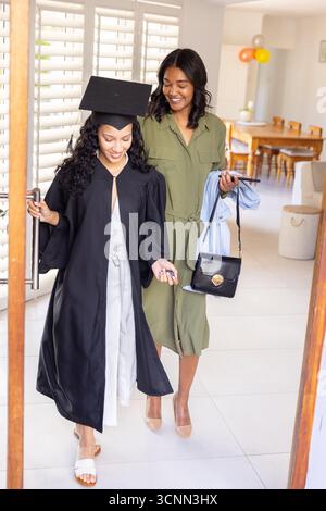 Mamma e figlia adolescente diverse che tengono in mano le chiavi e il mortaio mentre entrano nell'ingresso Foto Stock