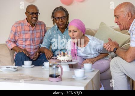 Diversi amici anziani festeggiano il compleanno in salotto con torta, tazze da caffè, stampa francese Foto Stock