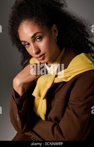 Outfit alla moda per l'autunno su una bella donna afroamericana che posa in uno studio con fiducia. Foto Stock