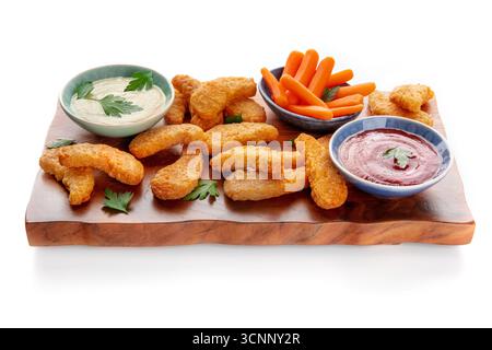 Pepite di pollo con verdure fresche e tuffati su una tavola di legno, su sfondo bianco Foto Stock