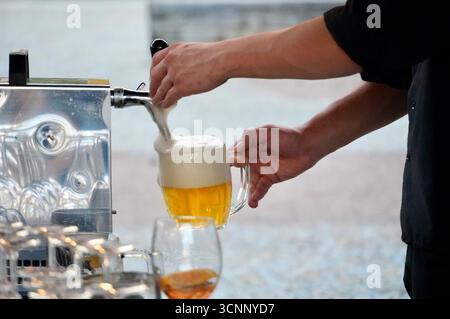 Barman che versa birra in un bicchiere dalla macchina per il caffè, primo piano Foto Stock