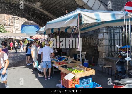 Il mercato della frutta all'aperto è affollato e ospita numerosi negozi per la scena estiva Catania, Italia, 22 settembre 2025 Foto Stock