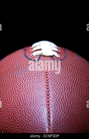 Un primo piano di un football americano rivela una texture dettagliata della pelle e cuciture precise, fotografate in uno studio su sfondo nero, Highli Foto Stock