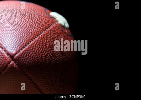 Un primo piano di un football americano rivela una texture dettagliata della pelle e cuciture precise, fotografate in uno studio su sfondo nero, Highli Foto Stock