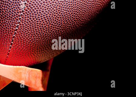 Un primo piano di un football americano rivela una texture dettagliata della pelle e cuciture precise, fotografate in uno studio su sfondo nero, Highli Foto Stock