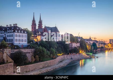 Basilea, Svizzera - Vista della riva sinistra del Reno con la città vecchia e la cattedrale di Baseler Munster al crepuscolo Foto Stock