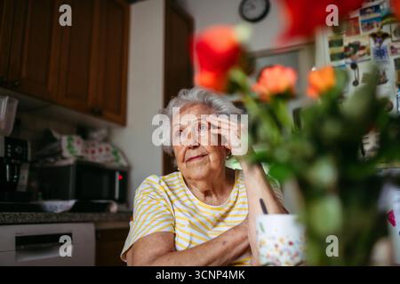 Ritratto di una donna anziana preoccupata seduta in cucina. Foto Stock