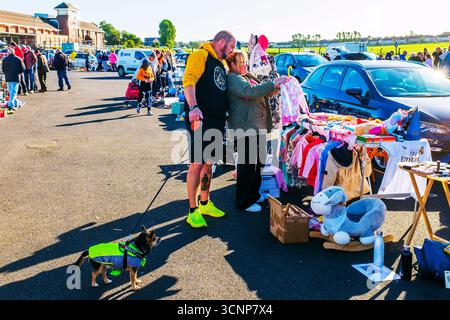 Uomo e donna che guardano i vestiti di seconda mano da una stalla in un mercato di strada, Ayr, Ayrshire, Scozia, Regno Unito Foto Stock