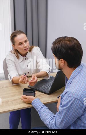 Otolaringologo che mostra moderni apparecchi acustici in miniatura per uomo di mezza età presso il moderno centro medico. Audiologo aiuta a valutare i disturbi dell'udito Foto Stock