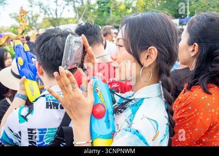 2025 Songkran Festival, Bangkok, Thailandia. Donna che partecipa al festival che scatta una foto con uno smartphone in custodia impermeabile; talco in polvere sul viso Foto Stock