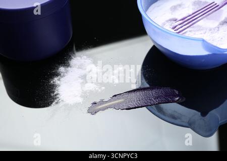 Prodotto cosmetico per capelli biondi e polvere sulla superficie dello specchio, primo piano Foto Stock
