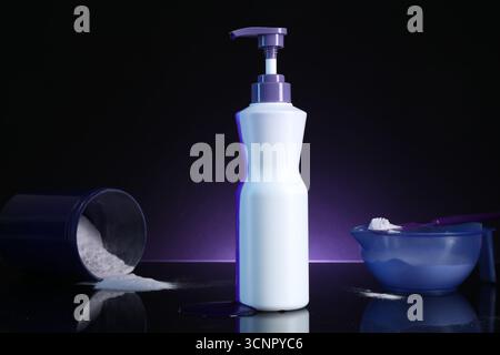 Prodotto cosmetico per la cura dei capelli per capelli biondi e polvere su superficie a specchio nera su sfondo viola scuro Foto Stock