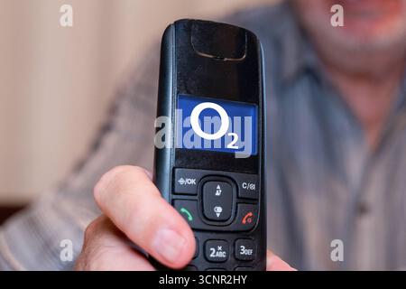 Germania - 21 settembre 2025: FOTOMONTAGGIO, un anziano tiene in mano un telefono fisso con il logo del fornitore di telefonia mobile O2 *** FOTOMONTAGE, Ein älterer Mann hält ein Festnetz Telefon in der Hand mit dem Logo vom Mobilfunk und Telefonanbieter O2 Foto Stock