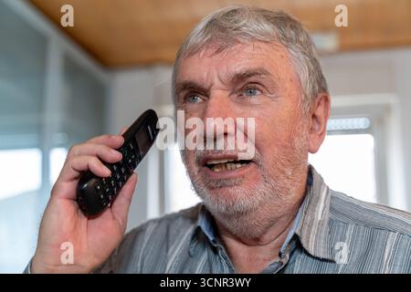 Germania - 21 settembre 2025: Un uomo anziano sta parlando al telefono. L'immagine simboleggia le truffe telefoniche come la truffa dei nipoti, che si rivolge specificamente agli anziani, e sottolinea la necessità di avvertimenti e misure protettive. *** Ein älterer Mann spricht am Telefon. DAS Bild symbolisiert Telefonbetrug wie den Enkeltrick, der gezielt Senioren ins Visier nimmt und zeigt die Notwendigkeit von Warnungen und Schutzmaßnahmen. Foto Stock