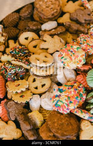 Colorato assortimento di biscotti e dolcetti al forno esposti su un vassoio durante una riunione di festa Foto Stock