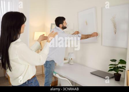 Coppia che decora la casa e appende Un'immagine sulla parete Foto Stock