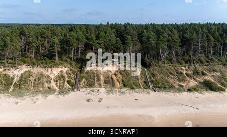 Volo in droni sopra la ripida costa di Jurkalne in Una giornata estiva di sole che rivela la costa del Mar Baltico sentieri sabbiosi campi verdi e paesaggi naturali tranquilli Foto Stock