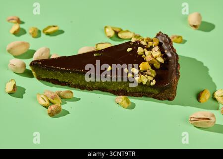 Decadent Chocolate Pistachio Slice presentato splendidamente su una tela di sfondo verde Foto Stock