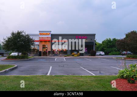 New Hartford, New York - 6 agosto 2025: Ampia vista serale dei negozi Dunkin' Donut e T-Mobile Foto Stock