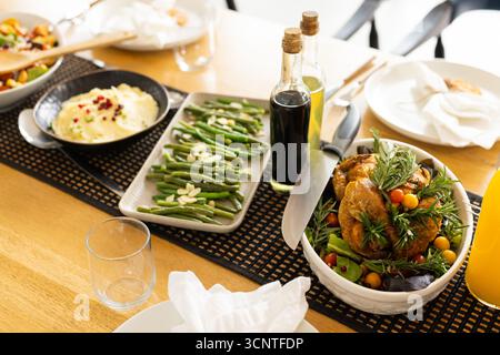 Recipiente bianco che serve pollo arrosto con purè di patate e fagiolini su un tavolo di legno Foto Stock