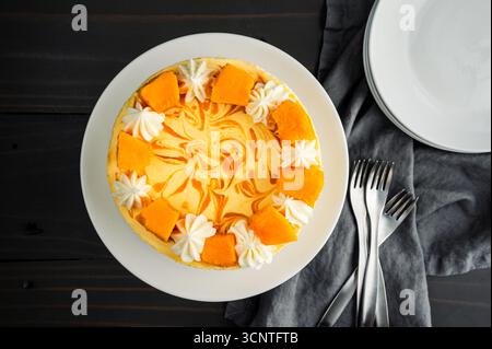 Mango Mousse Cake vista dall'alto: Direttamente sopra una mousse cake con vortice di mango, glassa di formaggio spalmabile e decorazioni di mango fresco Foto Stock