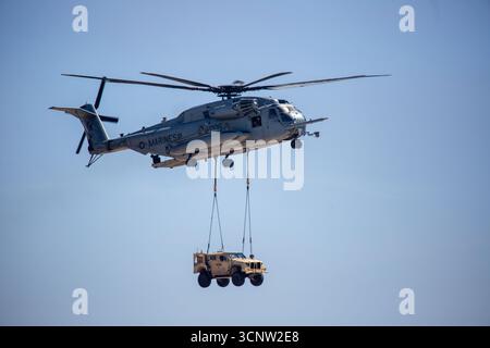 San Diego, California USA – 29 settembre 2024: Un Sikorsky CH-53E Super Stallion del corpo dei Marines degli Stati Uniti trasporta un Humvee HMMWV su un carico di imbracatura esterno durina Foto Stock