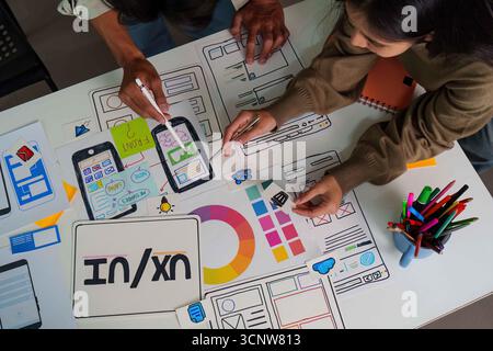 Processo creativo. Vista dall'alto dei progettisti che collaborano a strutture a reticolo e schizzi UX dell'interfaccia utente. Foto Stock