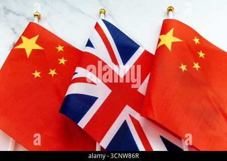 Il Regno Unito Union Jack sul palo di bandiera tra la bandiera nazionale cinese. Un concetto di relazioni tra Cina e Regno Unito. Foto Stock