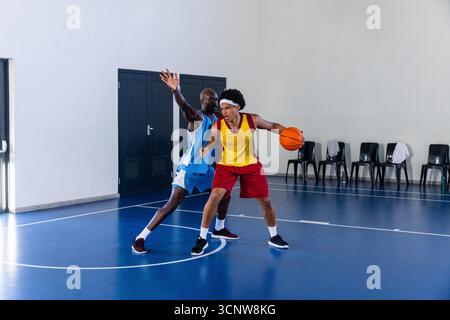 Giocatori di basket afroamericani in maglie dribbling ball sul campo con bottiglia d'acqua Foto Stock