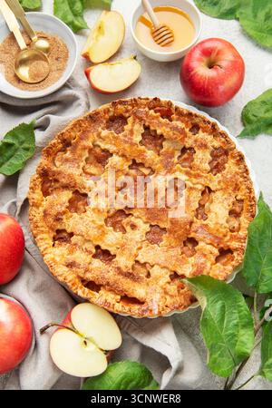 Classica torta di mele circondata da mele fresche, miele, zucchero di canna e decorata con foglie di mele Foto Stock