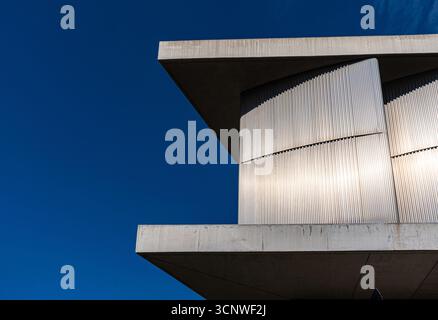 Vista astratta dell'architettura moderna con linee e superfici pulite. Le caratteristiche includono strutture in cemento e metallo sotto un cielo azzurro vivace, un altipiano Foto Stock