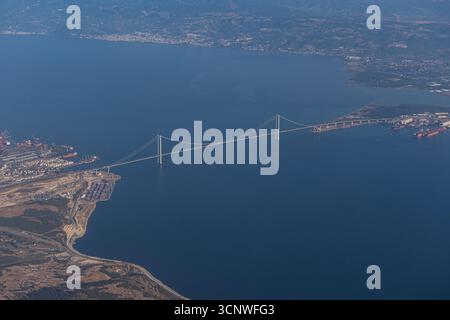 Una splendida vista aerea da un aeroplano cattura l'ampia costa greca e un maestoso ponte che si estende attraverso le acque blu profonde, che circondano Foto Stock