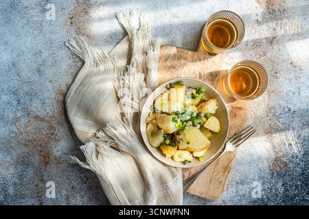 Una deliziosa insalata di patate greche con teneri patate, capperi piccanti ed erbe fresche. Servito in un ambiente rustico, questo piatto offre un assaggio di medi Foto Stock