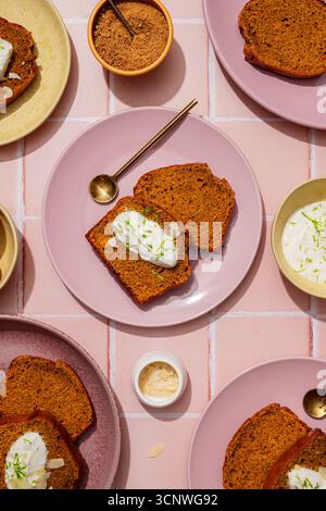 Vista dall'alto delle deliziose fette di torta di carote fatte in casa su piatti rosa con bambole di panna. Questa vivace immagine Highli è impreziosita da uno sfondo rosa piastrellato Foto Stock