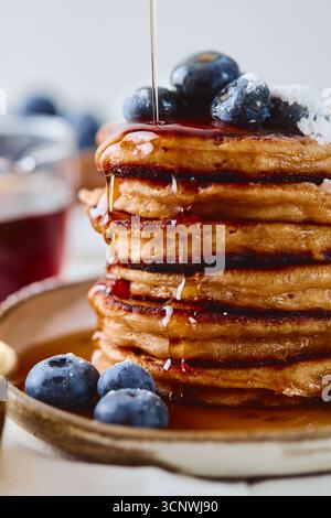 Una deliziosa pila di soffici pancake guarniti con mirtilli freschi e conditi con sciroppo dorato. Perfetto per una deliziosa colazione o un brunch Foto Stock