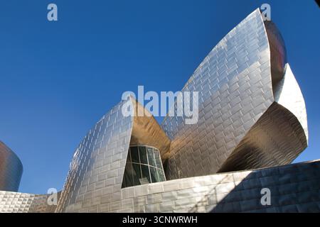 Guggenheim Museum Bilbao sotto il cielo blu. - La splendida facciata del Museo Guggenheim, con i suoi esclusivi pannelli in titanio che riflettono il sole luminoso sotto una cl Foto Stock