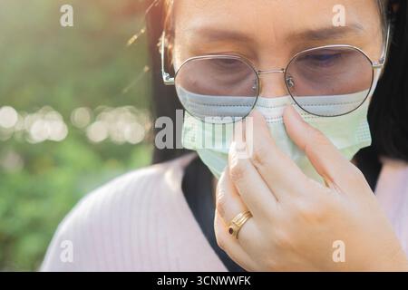 concetto di salute, sicurezza e pandemia. Primo piano ritratto di donna anziana in occhiali che indossano maschera medica protettiva per la protezione dal virus sopra il natur Foto Stock