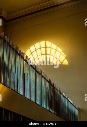 La luce del sole proietta un'ombra della finestra su un muro sopra un vecchio recinto di legno Foto Stock