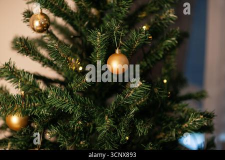 Primo piano di un albero di Natale splendidamente decorato, decorato con scintillanti ornamenti dorati e luci scintillanti, che catturano il calore e le festività Foto Stock