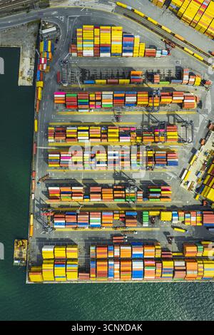 Vista aerea di vivaci container impilati in file ordinate sui moli, in contrasto con il mare blu profondo, Porto di la Spezia, Liguria, Italia. Foto Stock