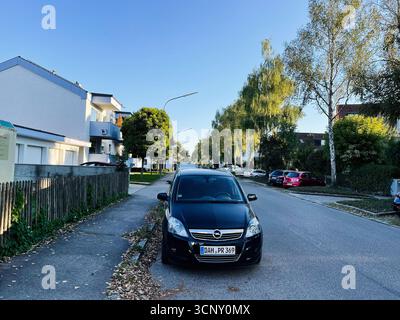 Dachau, Germania - 22 settembre 2022: Una Opel nera parcheggiata lungo una strada alberata tedesca residenziale in una giornata di sole. Foto Stock
