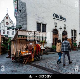 Vista sulla strada di Olde Hansa nella città vecchia di Tallinn, Estonia, con bancarelle medievali del mercato, venditori in costume e turisti che camminano per le strade acciottolate. Foto Stock